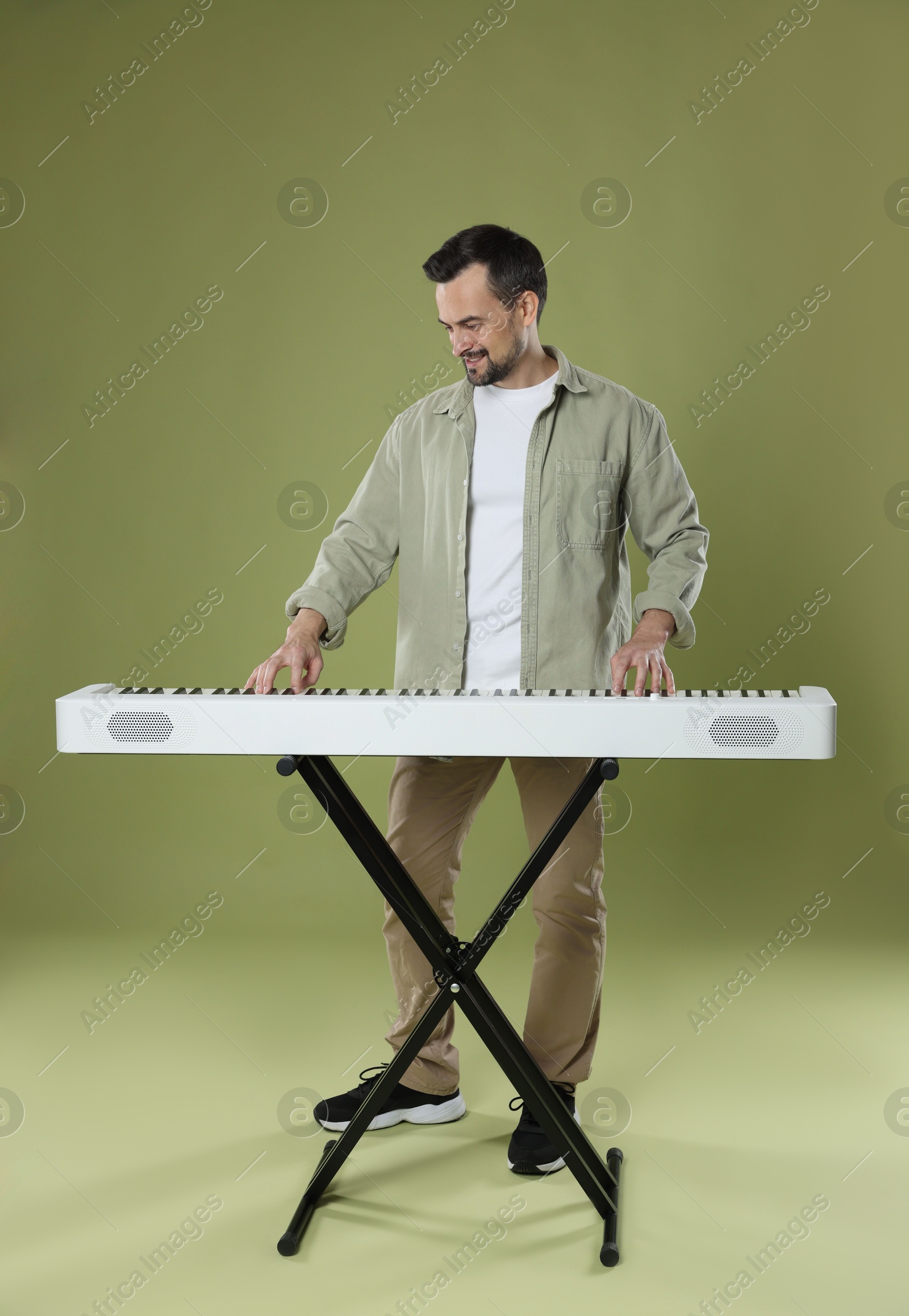 Photo of Bearded man playing synthesizer on olive background