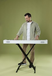 Photo of Bearded man playing synthesizer on olive background