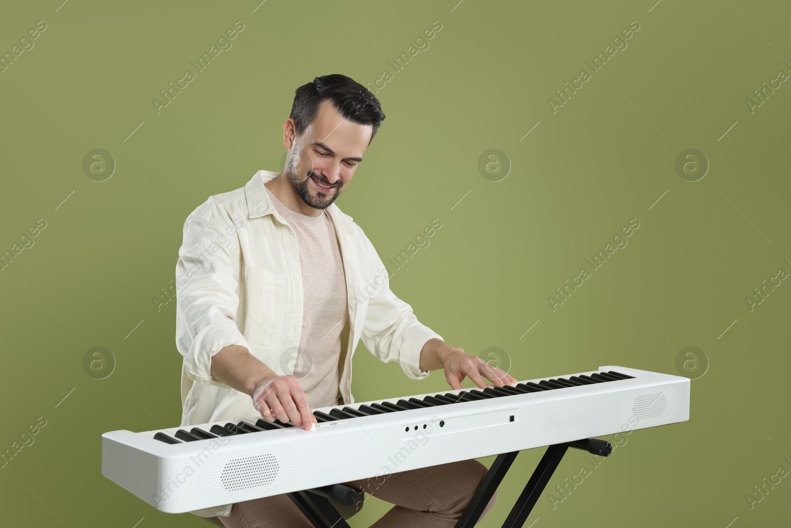 Photo of Bearded man playing synthesizer on olive background