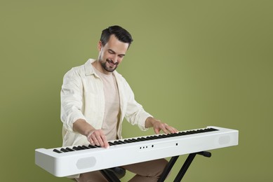 Photo of Bearded man playing synthesizer on olive background