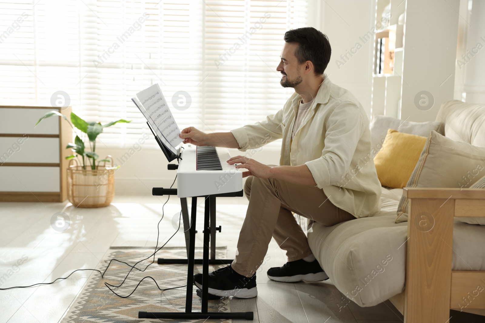 Photo of Bearded man playing synthesizer at home. Electronic musical instrument