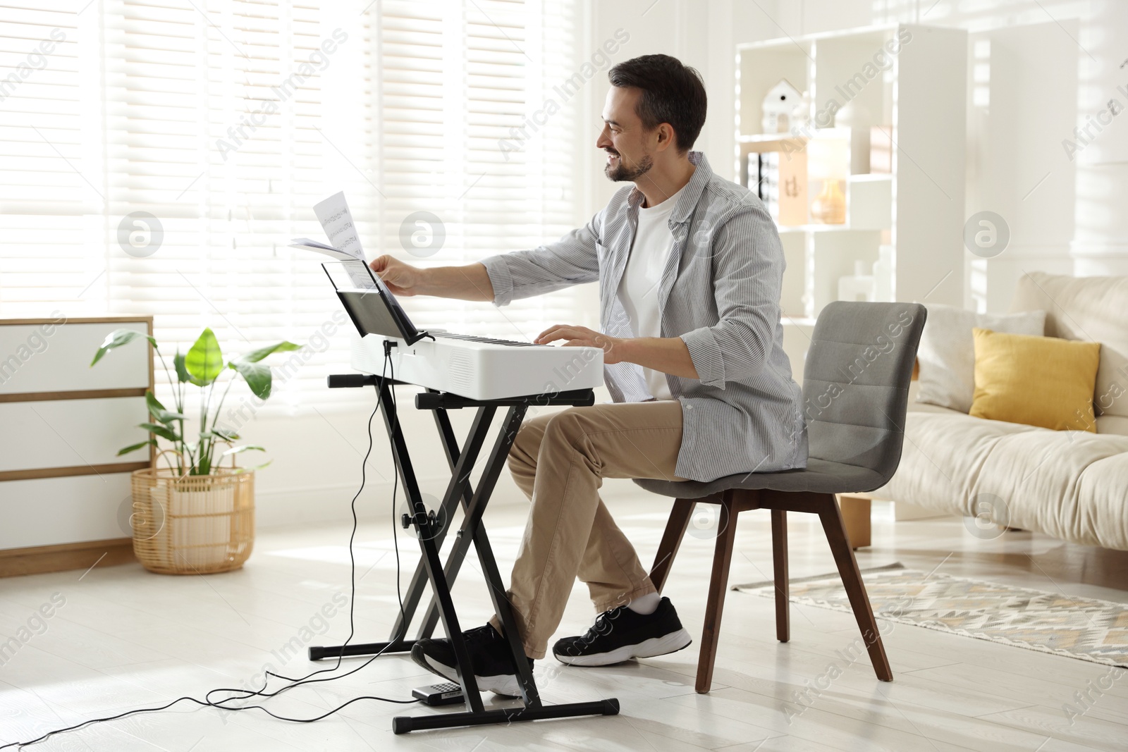 Photo of Bearded man playing synthesizer at home. Electronic musical instrument