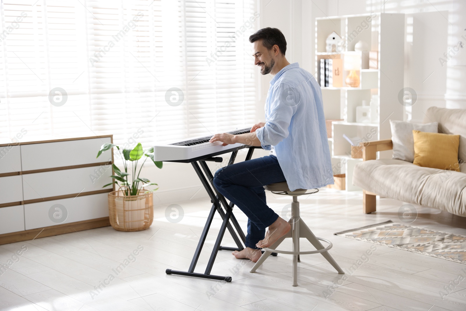 Photo of Smiling man playing synthesizer at home. Electronic musical instrument