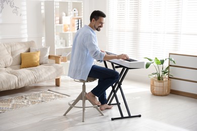 Photo of Smiling man playing synthesizer at home. Electronic musical instrument