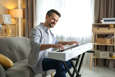 Photo of Smiling man playing synthesizer at home. Electronic musical instrument