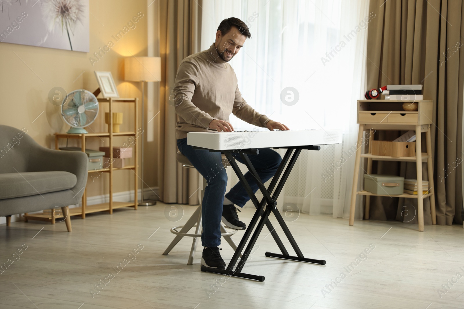 Photo of Smiling man playing synthesizer at home. Electronic musical instrument