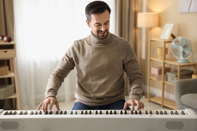 Photo of Smiling man playing synthesizer at home. Electronic musical instrument