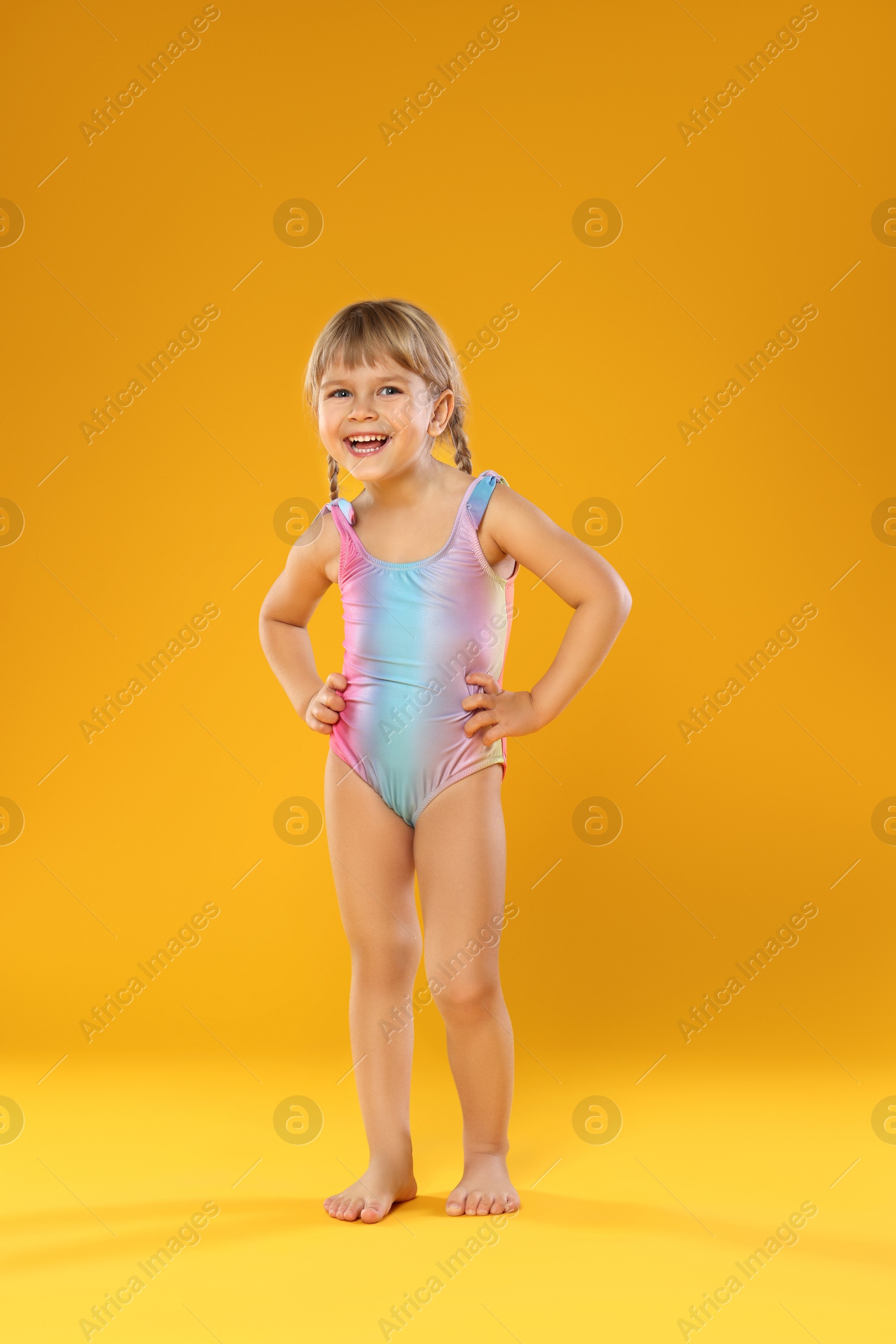 Photo of Cute little girl in swimsuit on orange background