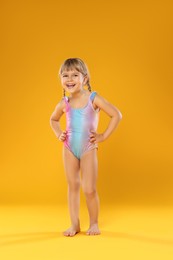 Photo of Cute little girl in swimsuit on orange background