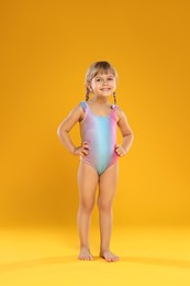 Photo of Cute little girl in swimsuit on orange background