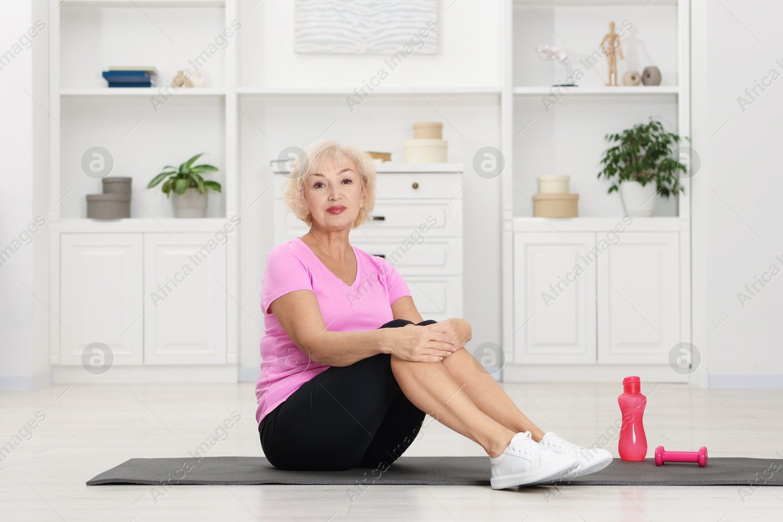 Photo of Senior woman exercising with fitness mat at home