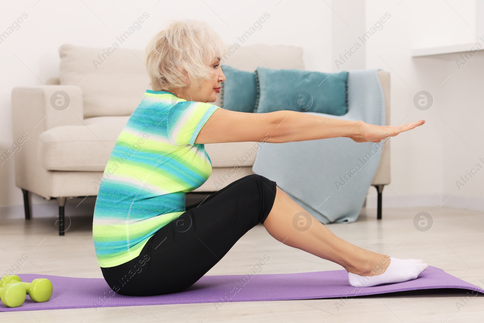 Photo of Senior woman exercising with fitness mat at home