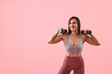 Photo of Woman in gym clothes exercising with dumbbells on pink background, space for text