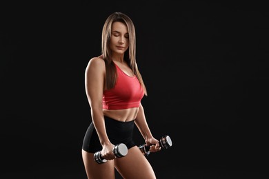 Photo of Woman in gym clothes exercising with dumbbells on black background, space for text