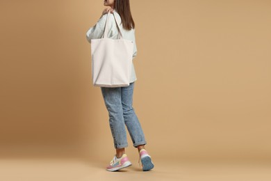 Photo of Woman with blank shopper bag on color background, closeup. Mockup for design