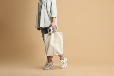 Photo of Woman with blank shopper bag on color background, closeup. Mockup for design