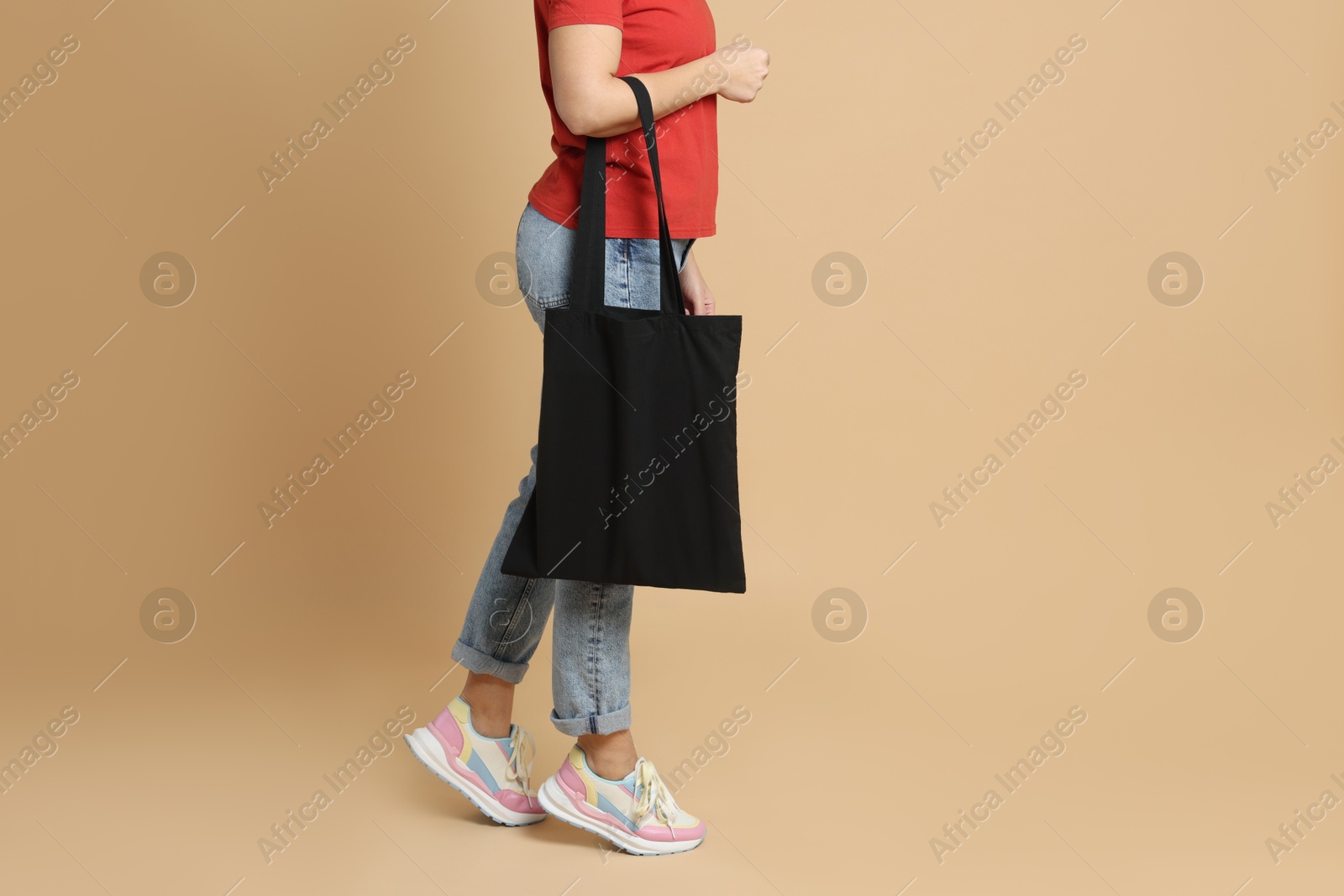 Photo of Woman with blank black shopper bag on color background, closeup. Mockup for design