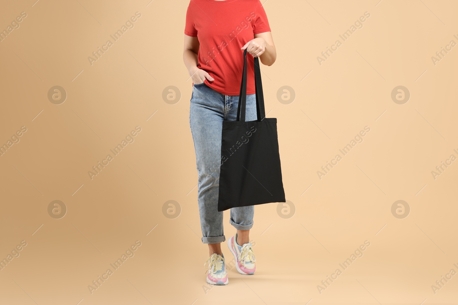 Photo of Woman with blank black shopper bag on color background, closeup. Mockup for design