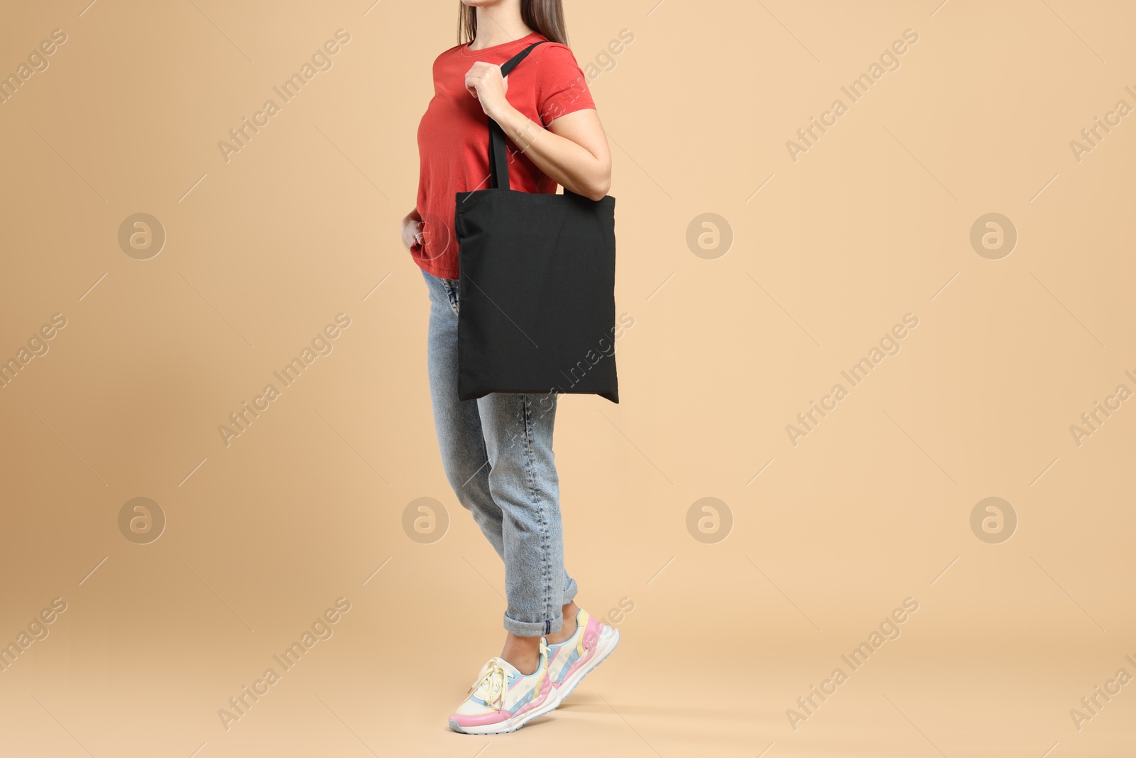 Photo of Woman with blank black shopper bag on color background, closeup. Mockup for design