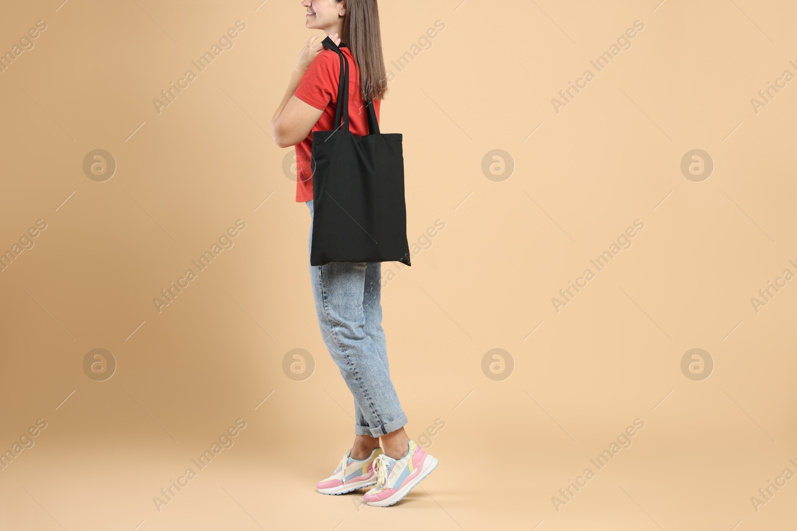 Photo of Woman with blank black shopper bag on color background, closeup. Mockup for design