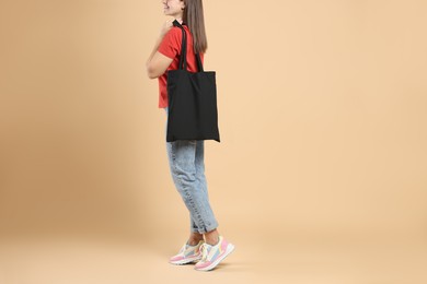 Photo of Woman with blank black shopper bag on color background, closeup. Mockup for design