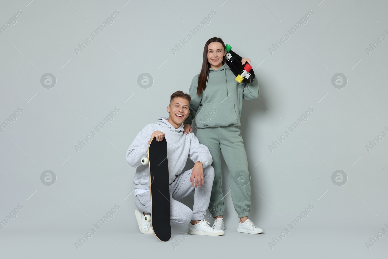 Photo of Happy friends with skateboards on light grey background