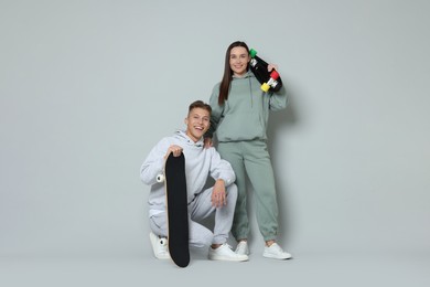 Photo of Happy friends with skateboards on light grey background