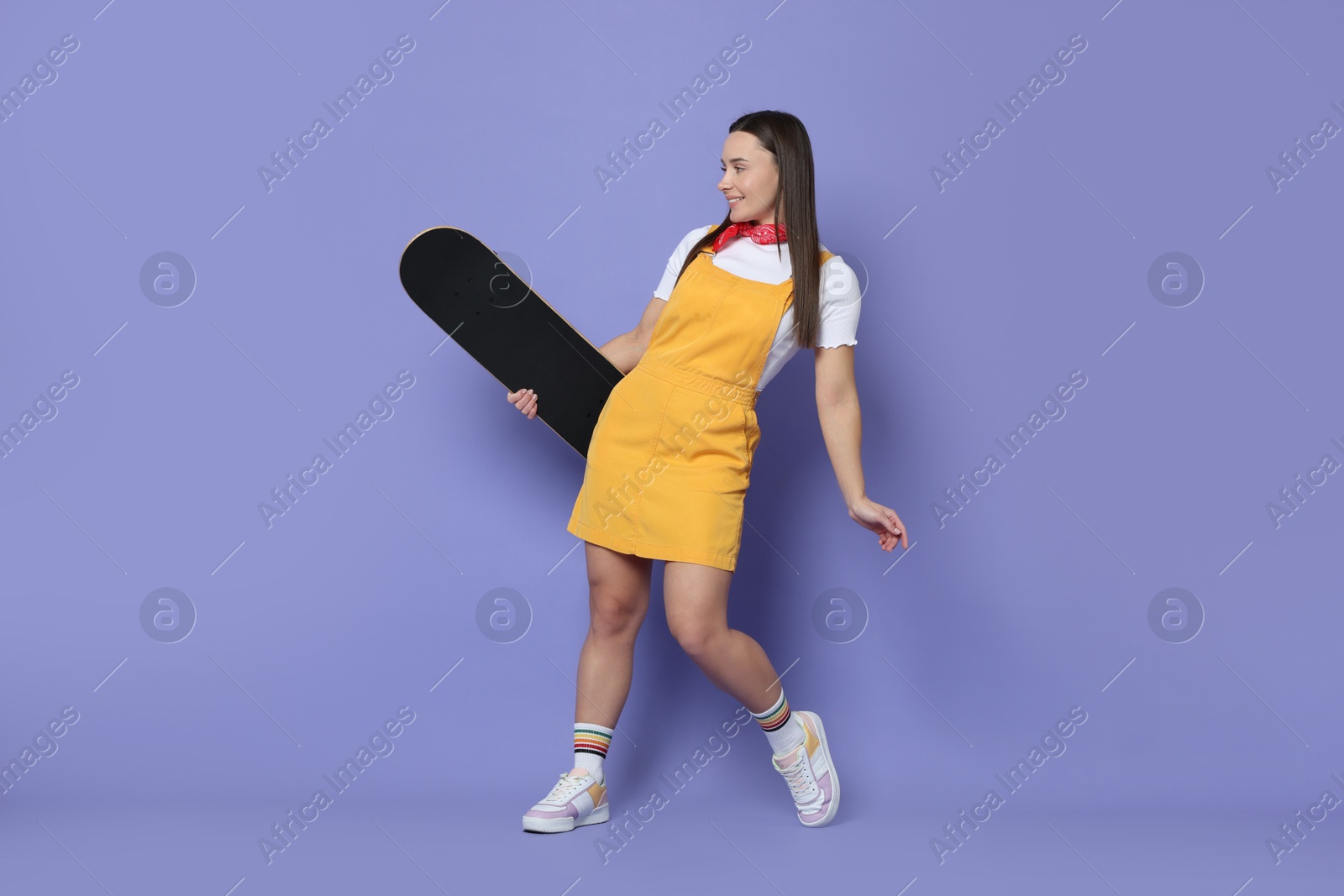 Photo of Smiling woman with skateboard on violet background