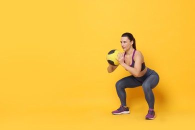 Photo of Beautiful woman with fitness ball training on yellow background. Space for text