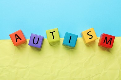 Photo of Word Autism made of colorful cubes on color background, top view