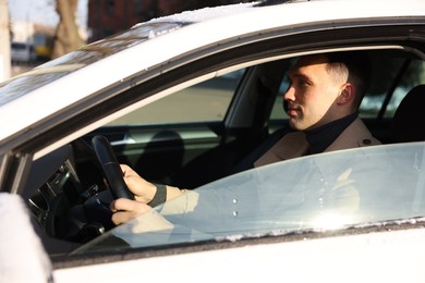 Photo of Driver behind steering wheel of modern car, view from outside