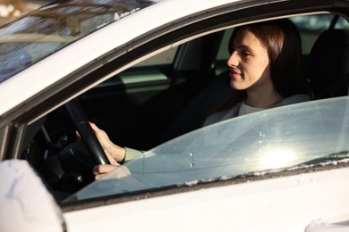 Photo of Driver behind steering wheel of modern car, view from outside