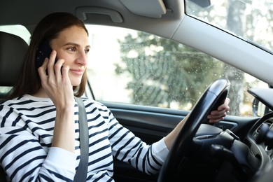 Photo of Driver talking on smartphone while driving modern car