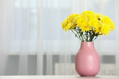 Photo of Beautiful yellow flowers in vase on table at home, space for text