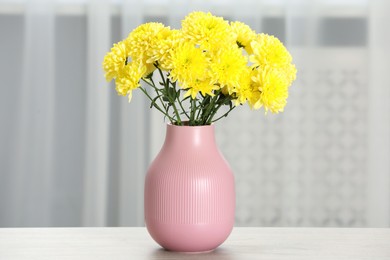 Photo of Beautiful yellow flowers in vase on table at home