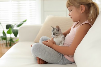 Photo of Little girl with cute kitten at home