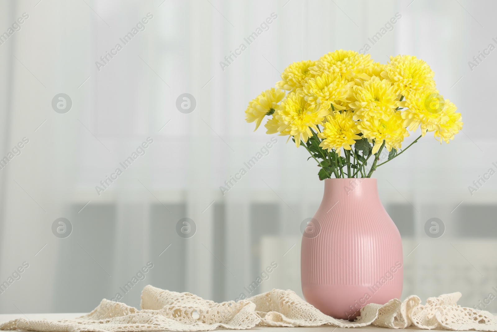 Photo of Beautiful yellow flowers in vase on table at home, space for text