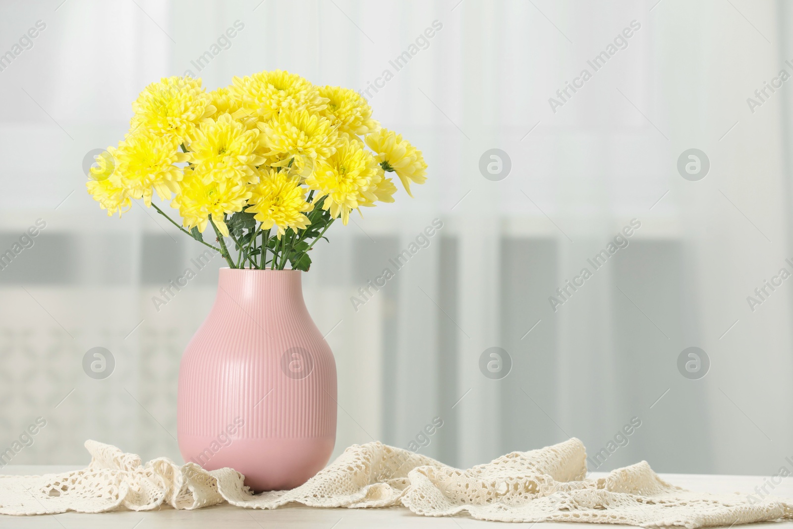 Photo of Beautiful yellow flowers in vase on table at home, space for text