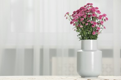 Photo of Beautiful pink flowers in vase on table at home, space for text