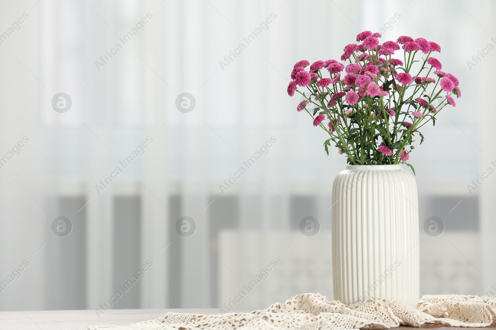 Photo of Beautiful pink flowers in vase on table at home, space for text