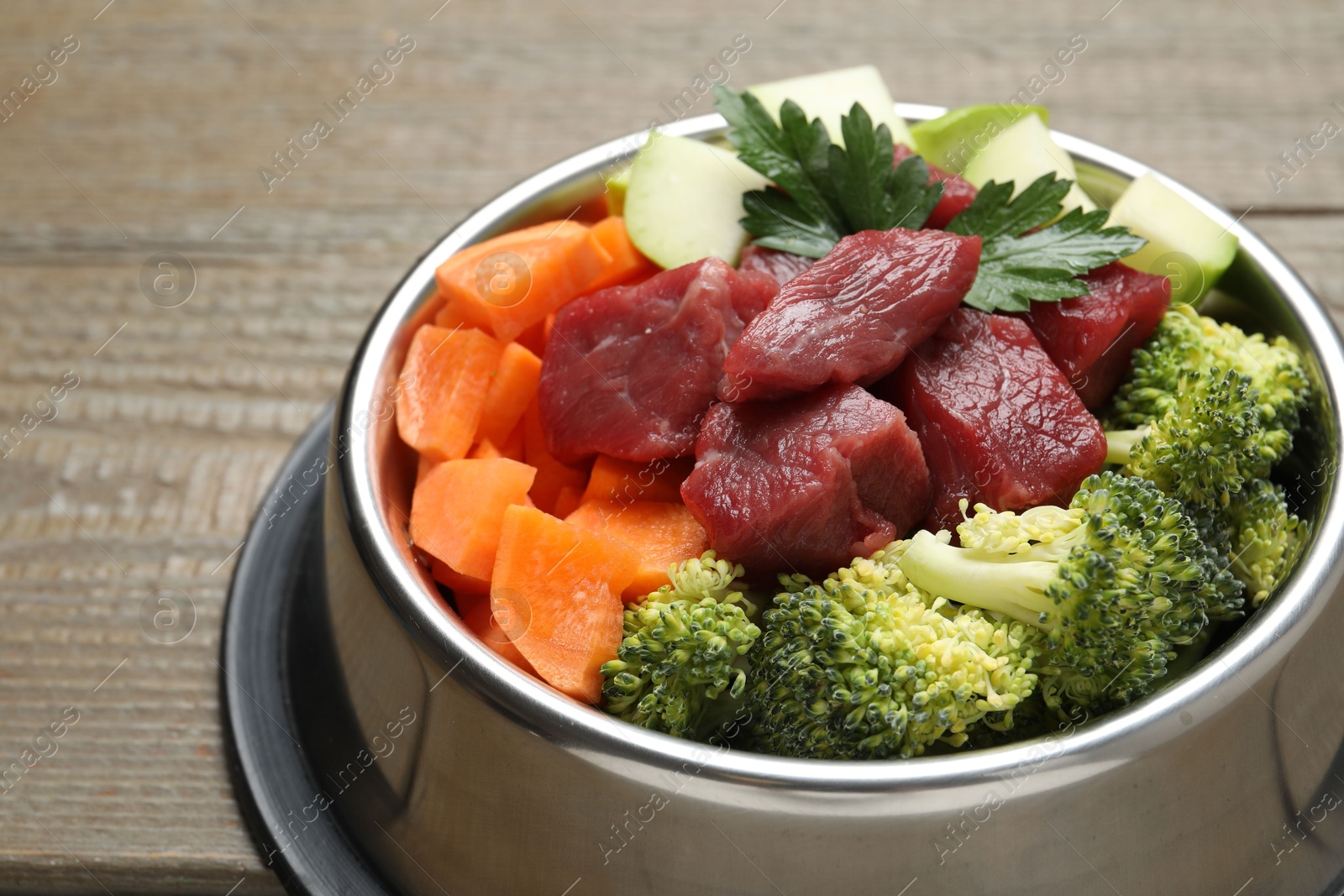 Photo of Fresh natural pet food in feeding bowl on wooden table, closeup