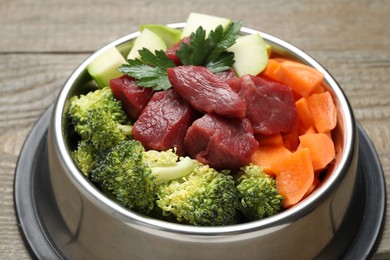 Photo of Fresh natural pet food in feeding bowl on wooden table, closeup