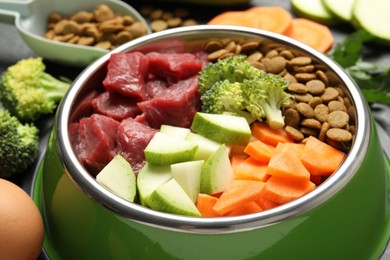 Photo of Natural and dry pet food in feeding bowl among products on table, closeup