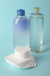 Photo of Clean cotton pads and micellar water on light blue background