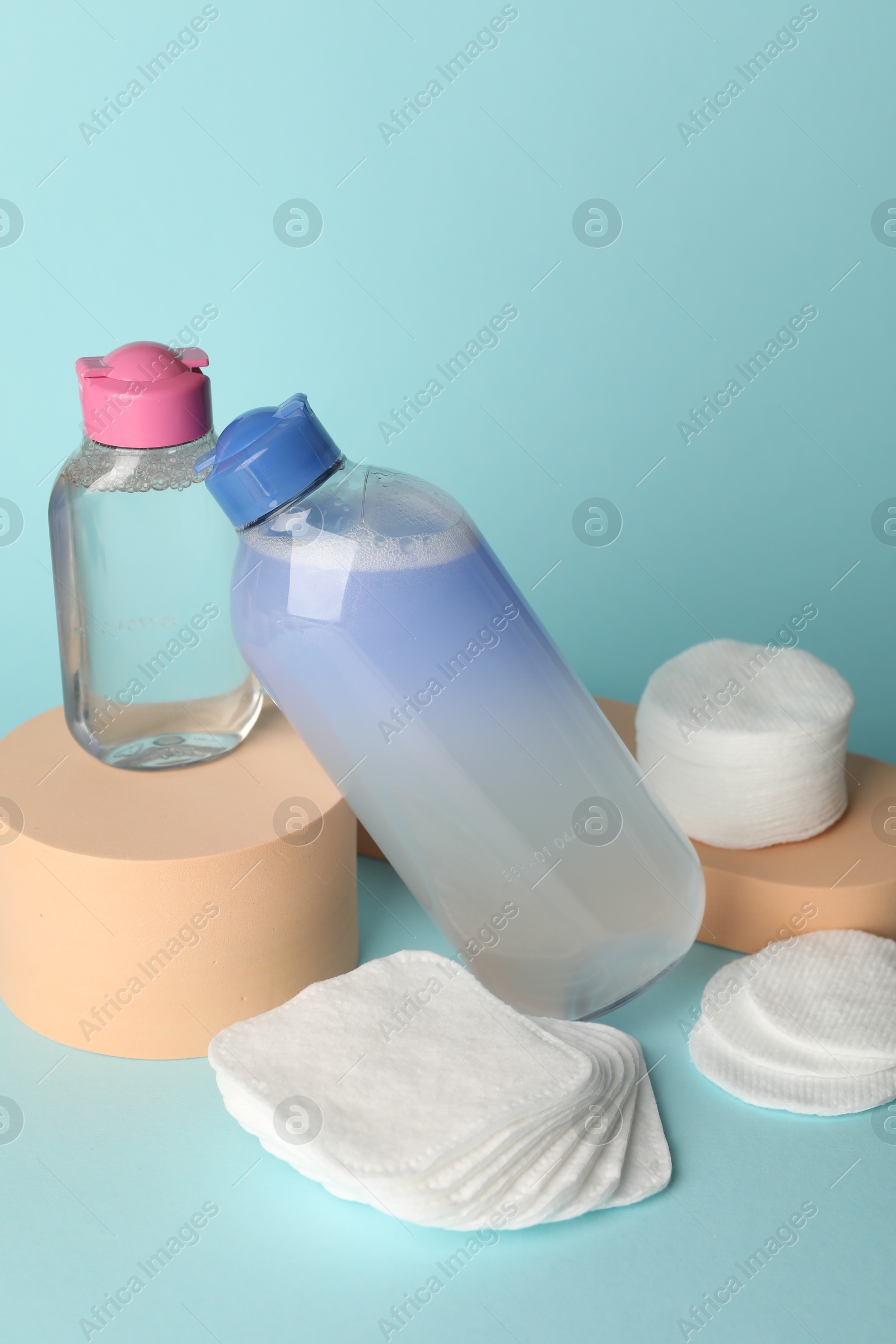 Photo of Clean cotton pads and micellar water on light blue background