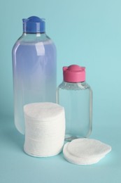 Photo of Clean cotton pads and micellar water on light blue background