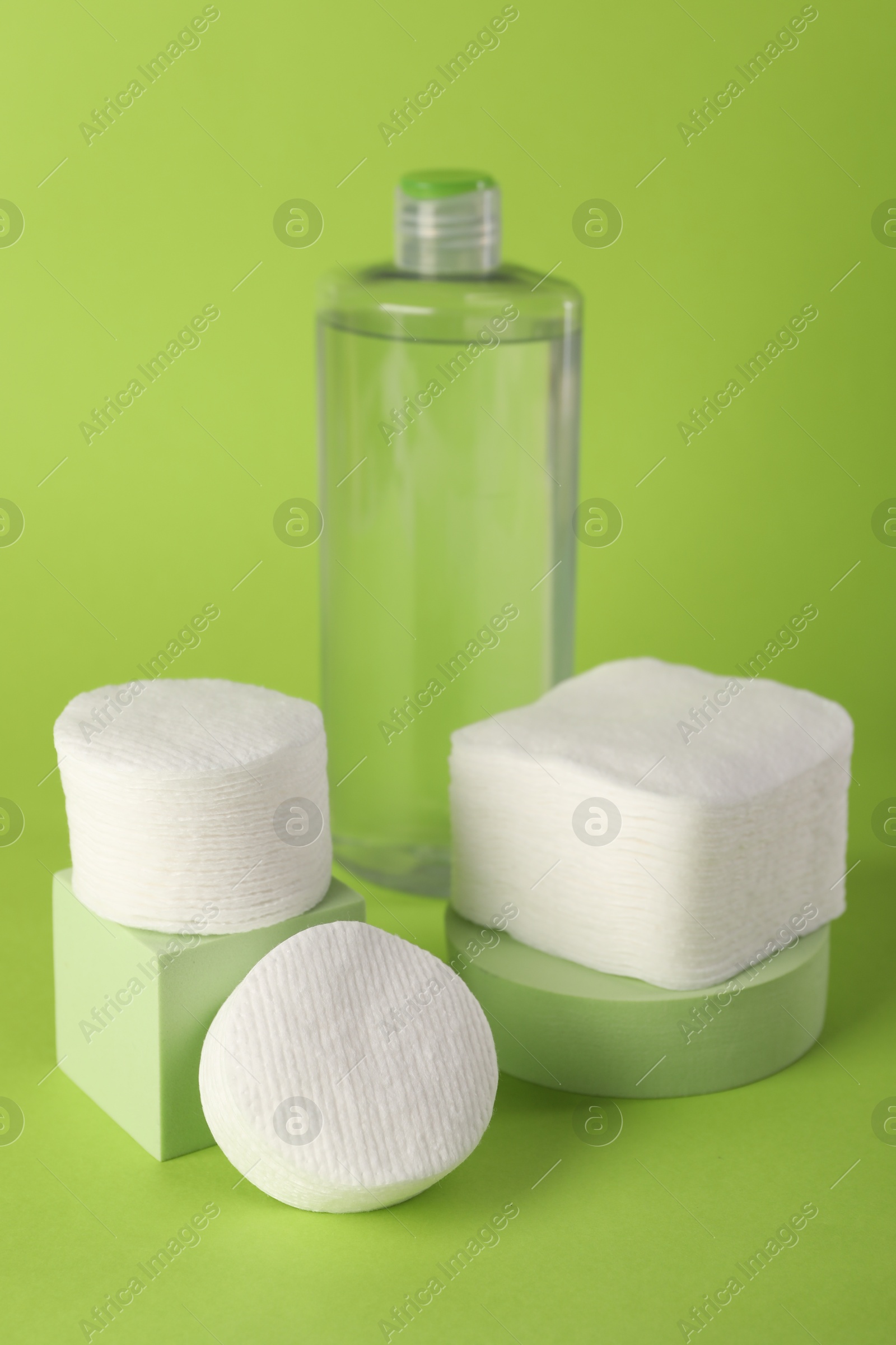 Photo of Clean cotton pads and micellar water on green background