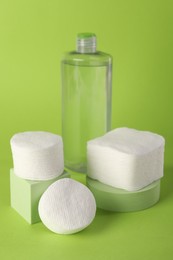 Photo of Clean cotton pads and micellar water on green background