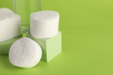 Photo of Clean cotton pads on green background, closeup. Space for text