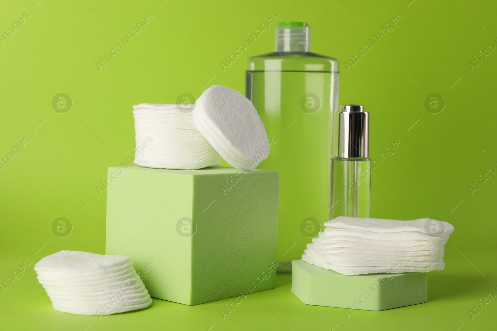 Photo of Clean cotton pads and cosmetic products on green background